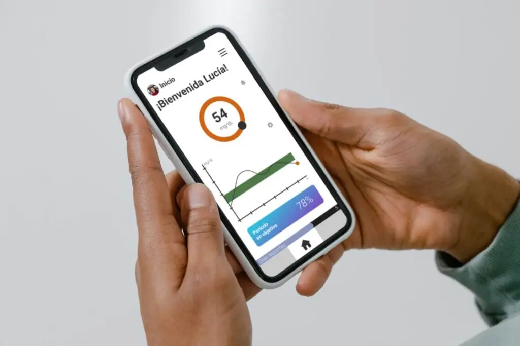 Aplicación móvil mostrando niveles de glucosa en sangre en tiempo real con un monitor continuo no invasivo.