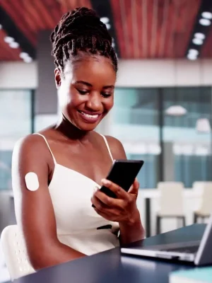 Mujer sonriente revisando su monitor continuo de glucosa no invasivo, con datos precisos en tiempo real.